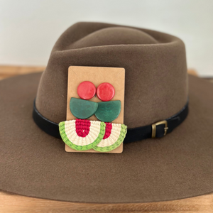 Brown hat with a decorative patch featuring red and green elements on a neutral background